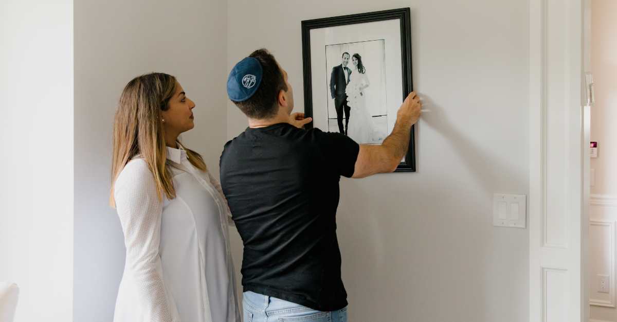 Couples watch their wedding video while their wedding photo is framed on the wall.